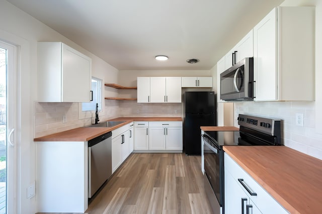 kitchen featuring open shelves, a sink, wooden counters, stainless steel appliances, and backsplash