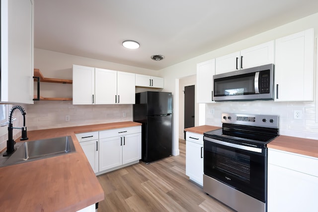 kitchen featuring appliances with stainless steel finishes, wood counters, a sink, and open shelves
