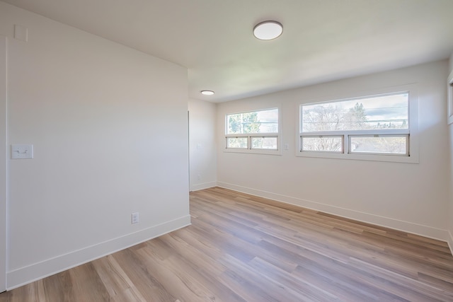 unfurnished room with light wood-type flooring and baseboards