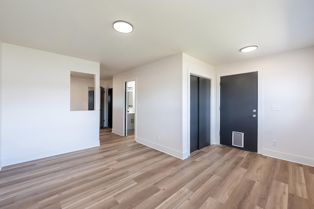 empty room with visible vents, light wood-type flooring, and baseboards