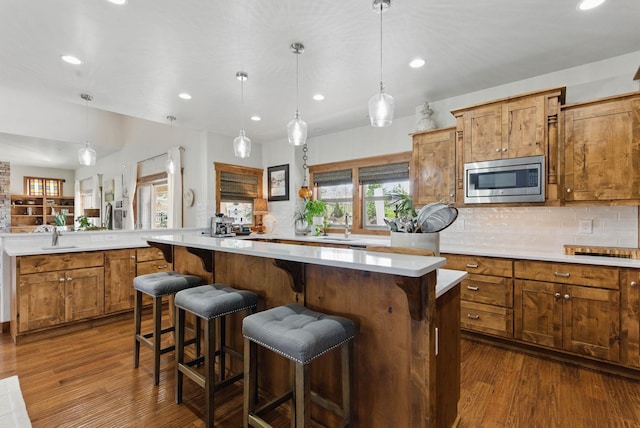 kitchen with light countertops, stainless steel microwave, a center island, and a healthy amount of sunlight