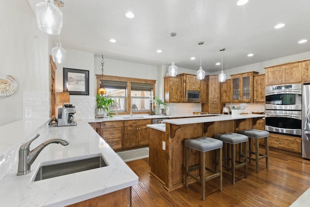 kitchen featuring recessed lighting, brown cabinets, a sink, and appliances with stainless steel finishes