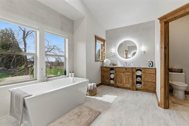 bathroom with a soaking tub, toilet, vanity, and vaulted ceiling