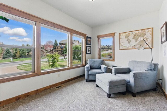 living area featuring visible vents, baseboards, and light carpet