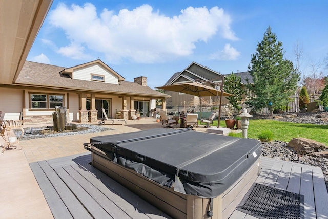 deck with a covered hot tub, fence, and a patio