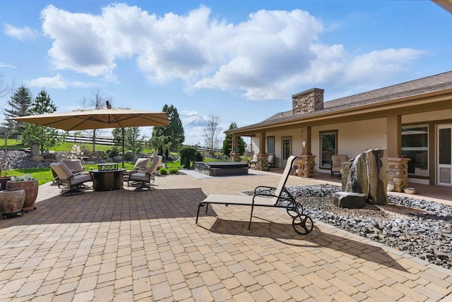 view of patio / terrace featuring an outdoor fire pit and a covered hot tub