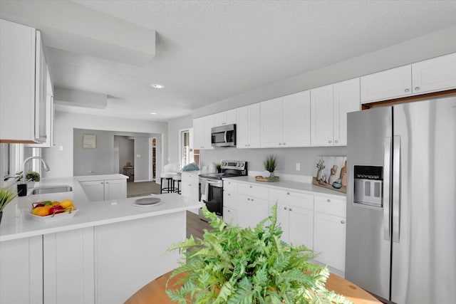 kitchen featuring a sink, light countertops, a peninsula, white cabinetry, and stainless steel appliances