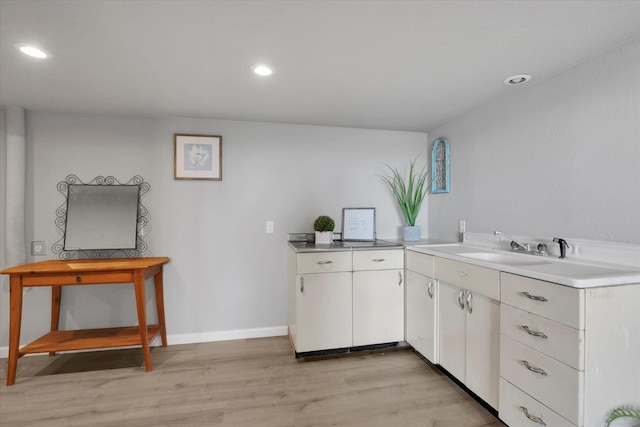 kitchen featuring recessed lighting, white cabinetry, light wood-style floors, and baseboards