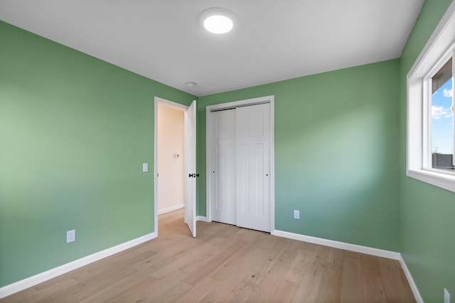 703 E Kiernan Ave, Spokane, WA 99207 - unfurnished bedroom with baseboards, light wood finished floors, and a closet