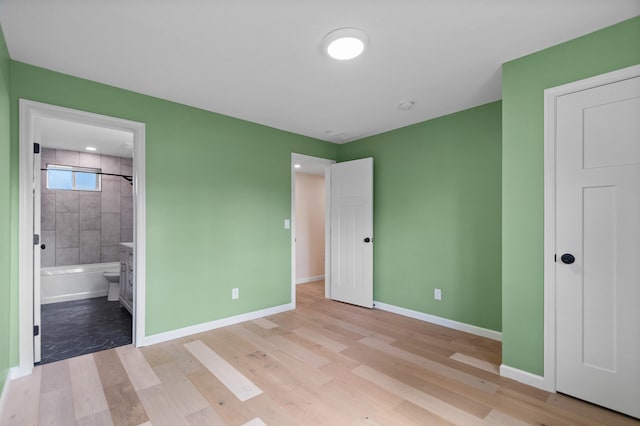 703 E Kiernan Ave, Spokane, WA 99207 - unfurnished bedroom with connected bathroom, baseboards, and light wood finished floors