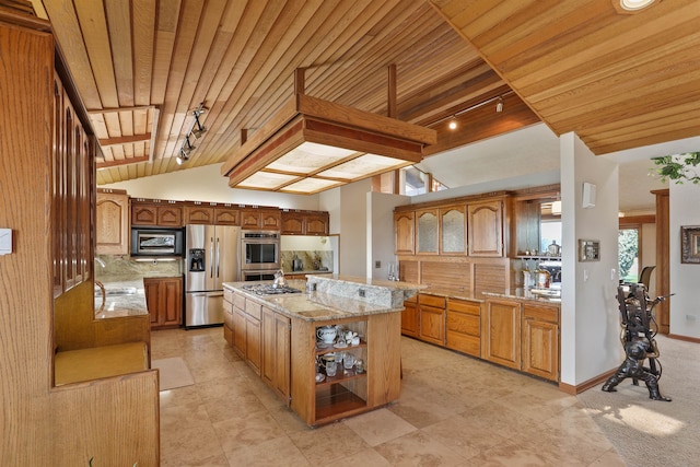 7816 E Gunning Ln, Spokane, WA 99212 - kitchen with stainless steel appliances, rail lighting, wood ceiling, light stone countertops, and brown cabinetry