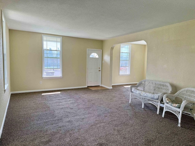 entrance foyer featuring arched walkways, plenty of natural light, and a textured ceiling