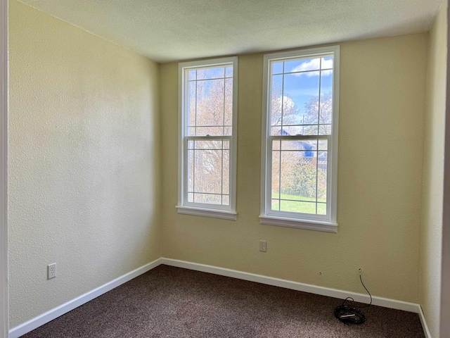 spare room with dark carpet, baseboards, a textured wall, and a textured ceiling