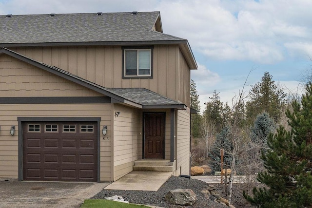 view of front facade featuring a garage, aphalt driveway, board and batten siding, and a shingled roof