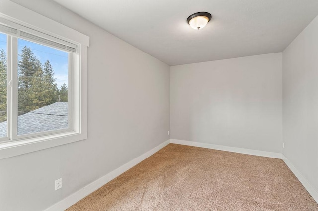 carpeted empty room featuring baseboards
