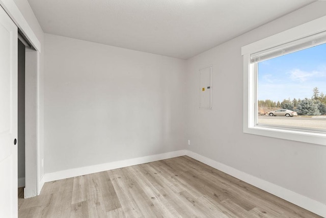 unfurnished bedroom with light wood-style floors, a closet, baseboards, and electric panel