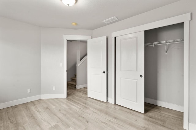 unfurnished bedroom with visible vents, baseboards, light wood finished floors, and a closet