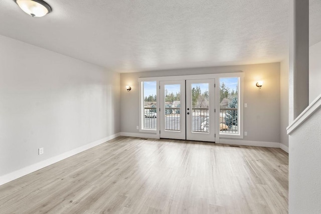 empty room featuring french doors, baseboards, wood finished floors, and a textured ceiling