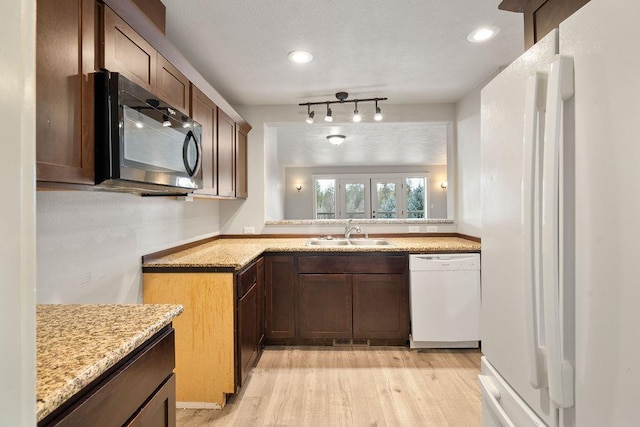 kitchen featuring light wood-type flooring, recessed lighting, white appliances, light stone countertops, and a sink