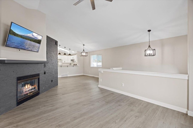 619 W Persimmon Ln, Spokane, WA 99224 - unfurnished living room featuring visible vents, baseboards, a stone fireplace, ceiling fan, and wood finished floors