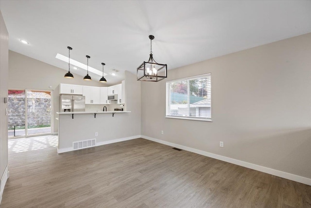 619 W Persimmon Ln, Spokane, WA 99224 - interior space featuring stainless steel fridge, a chandelier, white microwave, light countertops, and visible vents