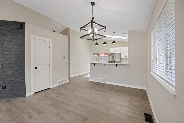 619 W Persimmon Ln, Spokane, WA 99224 - unfurnished living room featuring visible vents, vaulted ceiling, a chandelier, and light wood-style floors