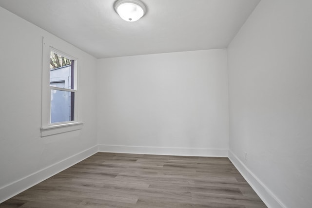 spare room featuring baseboards and wood finished floors