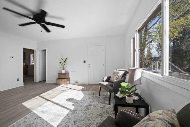 sitting room featuring baseboards, wood finished floors, and ceiling fan