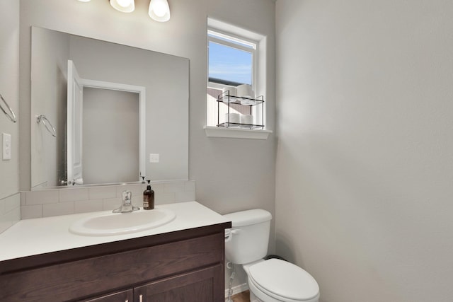 half bathroom with tasteful backsplash, toilet, and vanity
