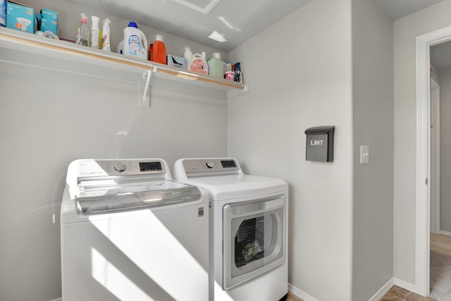 clothes washing area with separate washer and dryer and baseboards