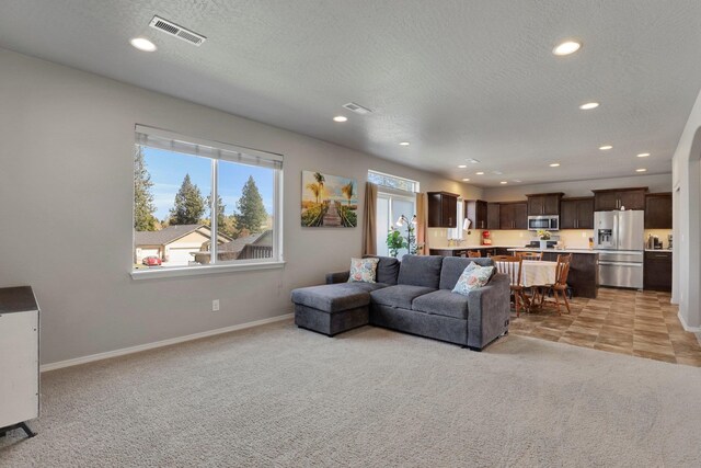 living area with recessed lighting, baseboards, light colored carpet, and a textured ceiling
