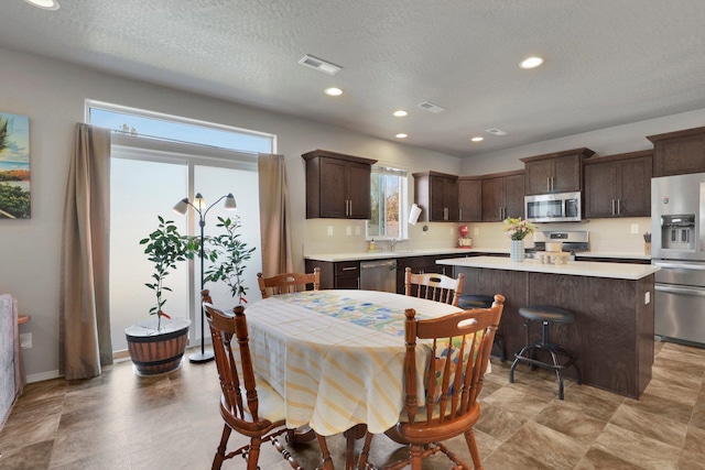 dining area with plenty of natural light, a textured ceiling, recessed lighting, and baseboards