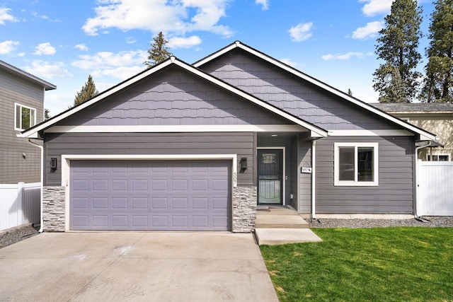 view of front of property with fence, driveway, stone siding, a front yard, and a garage