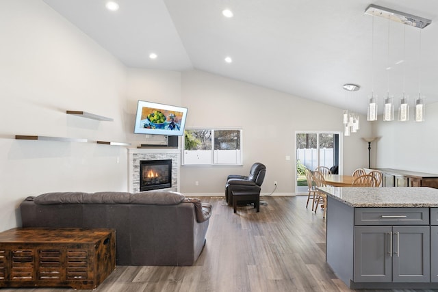living area featuring vaulted ceiling, baseboards, recessed lighting, wood finished floors, and a fireplace