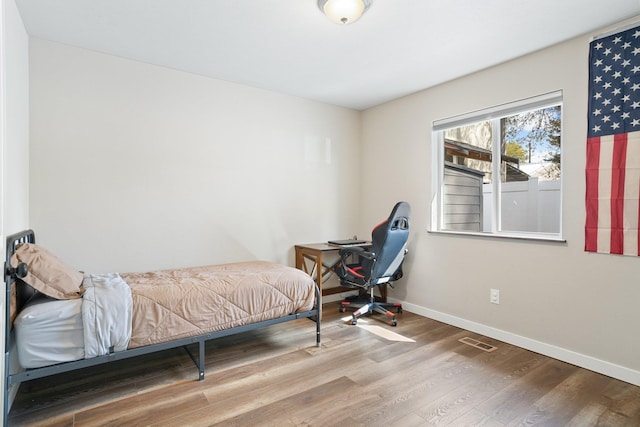 bedroom with baseboards, wood finished floors, and visible vents
