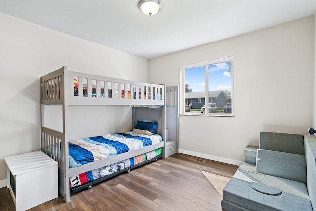 bedroom with wood finished floors, visible vents, and baseboards