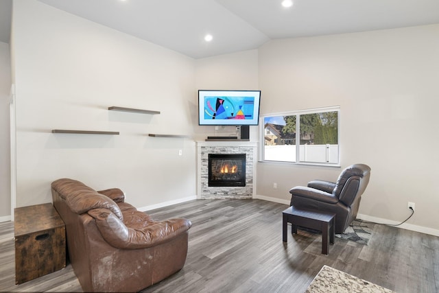 living room featuring a tile fireplace, lofted ceiling, wood finished floors, and baseboards