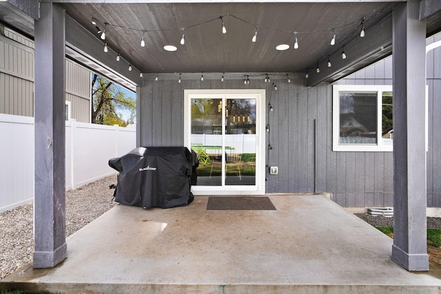 view of exterior entry featuring fence and a patio