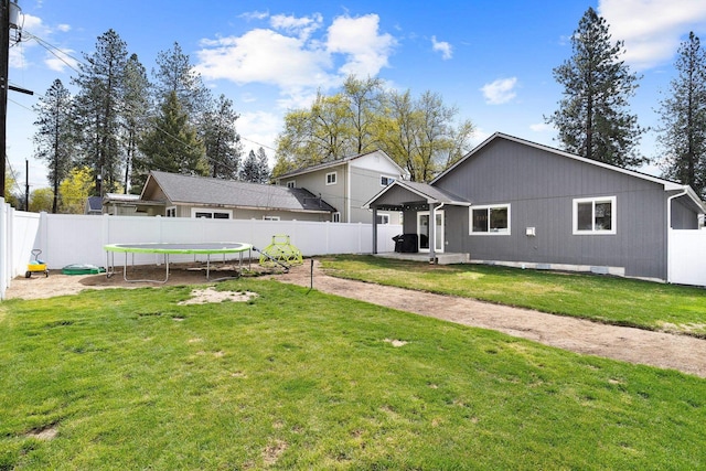 back of property featuring a fenced backyard, a yard, a patio, and a trampoline