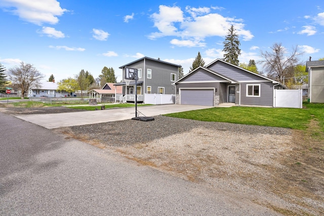 view of front of property featuring an attached garage, driveway, a front lawn, and fence