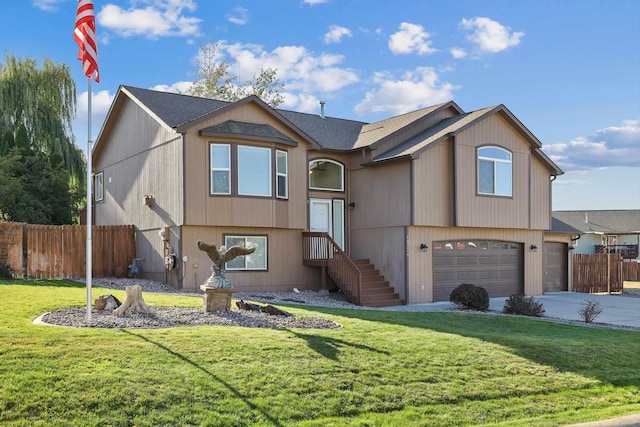 split foyer home with driveway, an attached garage, fence, and a front lawn