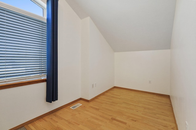 bonus room with visible vents, baseboards, light wood-type flooring, and vaulted ceiling