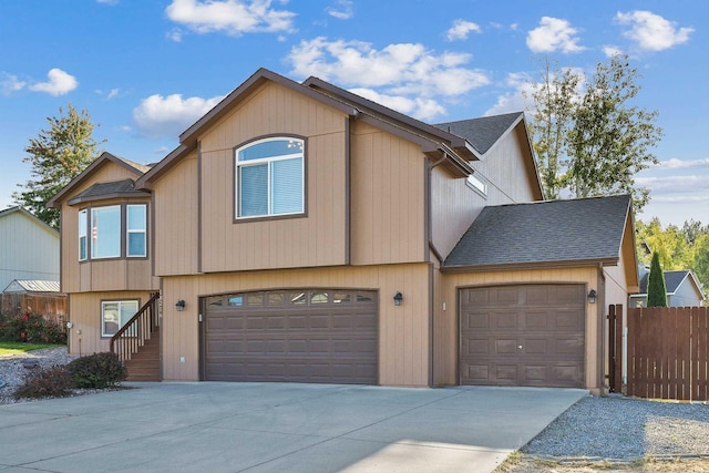 townhome / multi-family property with a garage, roof with shingles, driveway, and fence