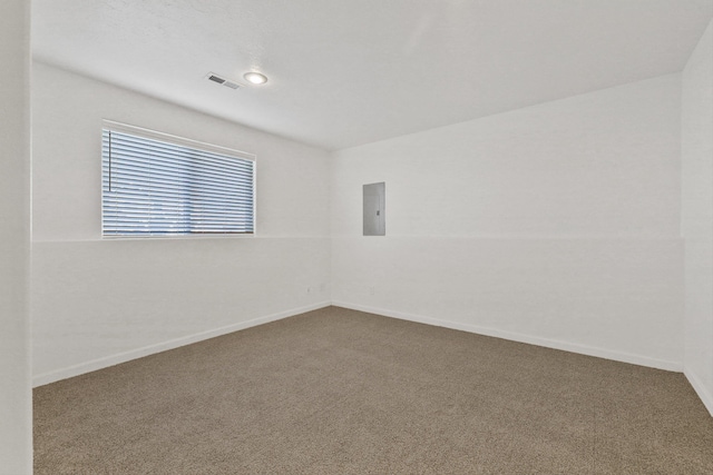 carpeted empty room with electric panel, visible vents, and baseboards