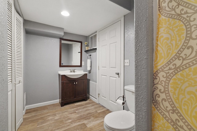 bathroom with vanity, a closet, baseboards, toilet, and wood finished floors