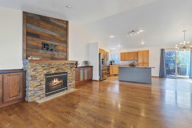 living room with high vaulted ceiling, an inviting chandelier, wood finished floors, and a fireplace