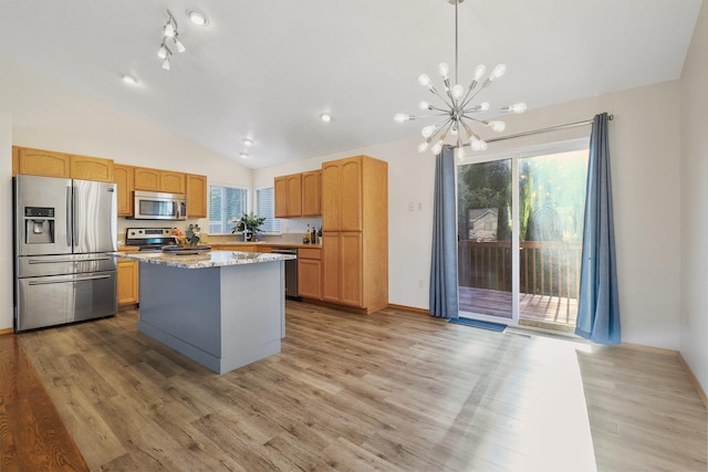 kitchen featuring light wood-style floors, vaulted ceiling, a center island, appliances with stainless steel finishes, and a notable chandelier