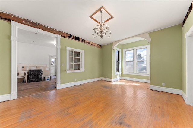 interior space with a notable chandelier, baseboards, beam ceiling, arched walkways, and wood-type flooring