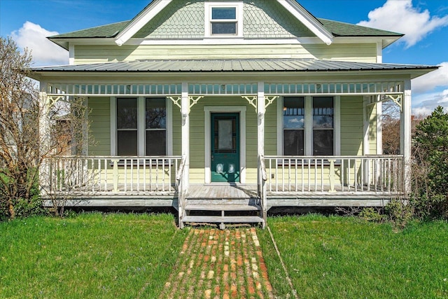 victorian-style house featuring a porch, metal roof, and a front lawn