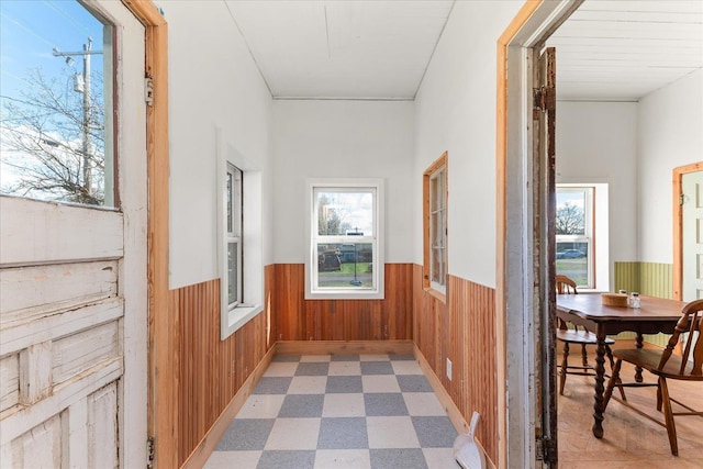 hall with wood walls, wainscoting, and light floors